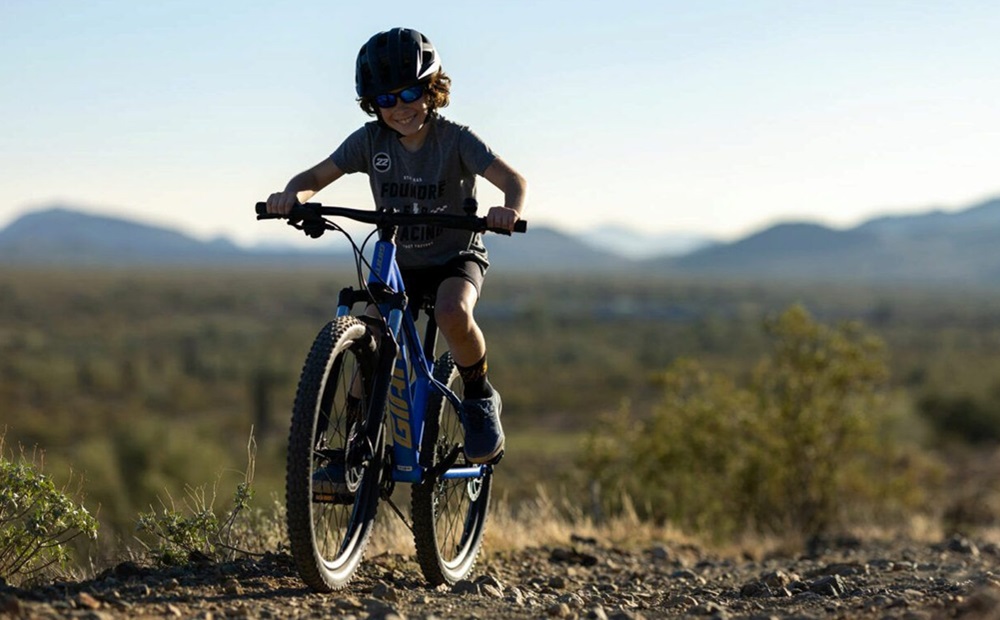 A junior boy on his bike smiling.